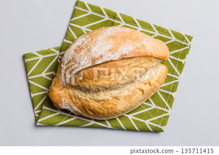 Freshly baked delicious french bread with napkin on rustic table top view. Healthy white bread loaf 135711415