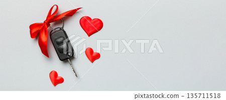 Car key with a red bow and a heart on Colored table. Giving present or gift for valentine day or christmas, Top view with copy space 135711518