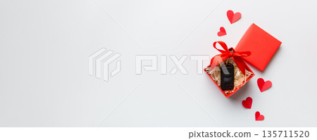 Black car key in a present box with a ribbon and red heart on colored background. Valentine day composition Top view Black car key in a present box with a ribbon and red heart on colored background. Valentine day composition Top view 135711520