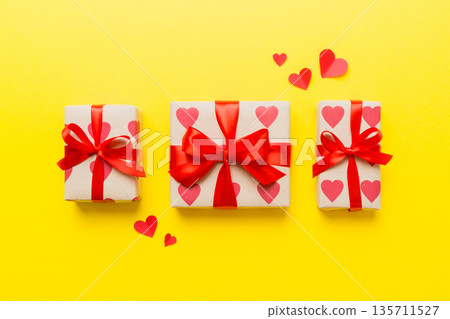 Top view photo of valentine day decorations gift box with red ribbon bow on colored background. Holiday gift boxes with top view Top view photo of valentine day decorations gift box with red ribbon bow on colored background. Holiday gift boxes with top view 135711527