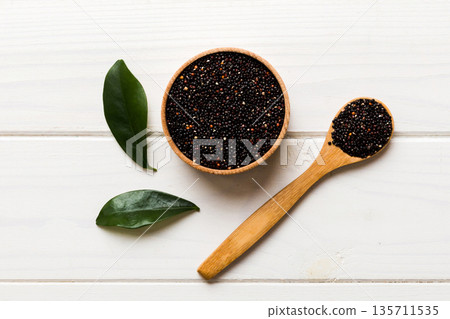 quinoa seeds in bowl and spoon on colored background. Healthy kinwa in small bowl. Healthy superfood quinoa seeds in bowl and spoon on colored background. Healthy kinwa in small bowl. Healthy superfood 135711535