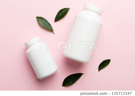 supplement pills with medicine bottle health care and medical top view. Vitamin tablets. Top view mockup bottle for pills and vitamins with green leaves, natural organic bio supplement, copy space 135711547