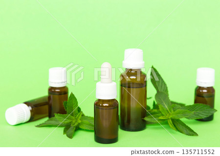 Natural Mint Essential Oil in a Glass Bottle. organic cosmetics with herbal extracts of mint on colored background 135711552