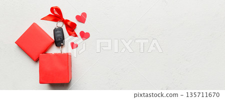 Black car key in a present box with a ribbon and red heart on colored background. Valentine day composition Top view Black car key in a present box with a ribbon and red heart on colored background. Valentine day composition Top view 135711670