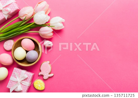 Easter frame with eggs, gift box and tulip on a colored background. The minimal concept. Top view Happy Easter composition. Card with a copy space of the place for the text 135711725