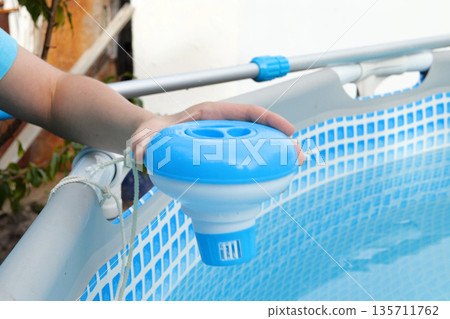Worker hands isinfection and chlorination of water in the pool. Purification from pollution pool chlor dispenser 135711762