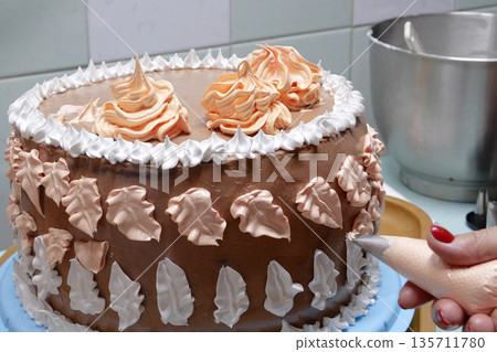 Confectioner woman is pouring cream on sponge cake using pastry bag, closeup view. Pastry chef is cooking homemade cake. cooking, baking and cooking, home cooking 135711780