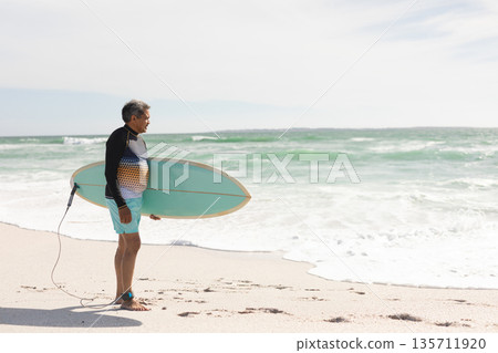Senior Hispanic male surfer wading barefoot on shore carrying blue surfboard with leash, copy space Senior Hispanic male surfer wading barefoot on shore carrying blue surfboard with leash, copy space 135711920