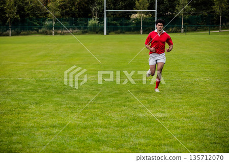 African American male athlete running across rugby pitch toward camera past goalposts, copy space African American male athlete running across rugby pitch toward camera past goalposts, copy space 135712070