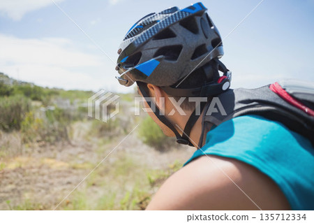 Male cyclist pausing and admiring scenery on narrow dirt trail with helmet and backpack, copy space Male cyclist pausing and admiring scenery on narrow dirt trail with helmet and backpack, copy space 135712334
