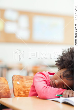 African American girl resting head on book with pencil at desk in classroom, copy space African American girl resting head on book with pencil at desk in classroom, copy space 135712360