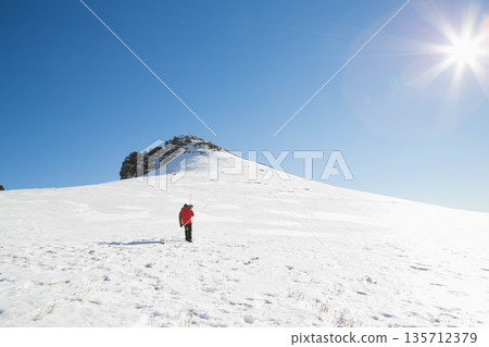 Man trekking on alpine slope wearing insulated jacket, carrying skis and backpack, copy space Man trekking on alpine slope wearing insulated jacket, carrying skis and backpack, copy space 135712379
