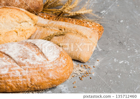 Homemade natural breads. Different kinds of fresh bread as background, perspective view with copy space Homemade natural breads. Different kinds of fresh bread as background, perspective view with copy space 135712460