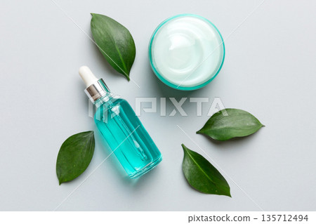 Organic cosmetic products with green leaves on color background. Flat lay Organic cosmetic products with green leaves on color background. Flat lay 135712494