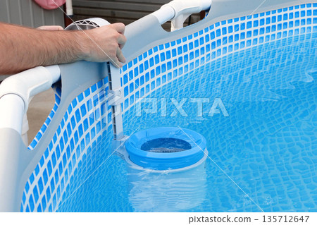Man cleans skimmer for the frame pool. Contaminated pool cleaning concept Man cleans skimmer for the frame pool. Contaminated pool cleaning concept 135712647