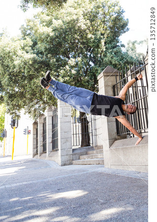 African American man holding human flag position on metal fence by stone pillars on urban sidewalk African American man holding human flag position on metal fence by stone pillars on urban sidewalk 135712849