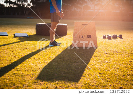 Male fitness enthusiast wearing athletic gear exercising at park with plyometric box, mats, tire Male fitness enthusiast wearing athletic gear exercising at park with plyometric box, mats, tire 135712932