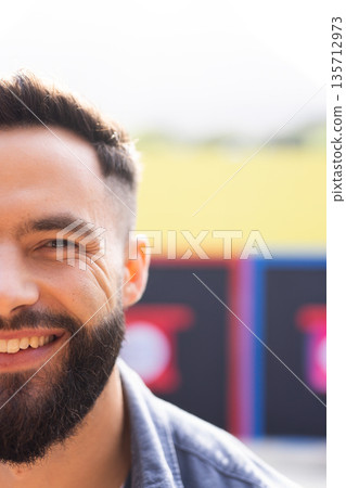 Adult male Smiling and wearing denim shirt while standing outside near bright sign, copy space 135712973