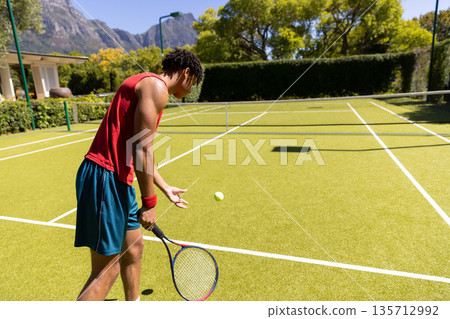 African American male serving tennis ball with racket on grass court near net, copy space African American male serving tennis ball with racket on grass court near net, copy space 135712992