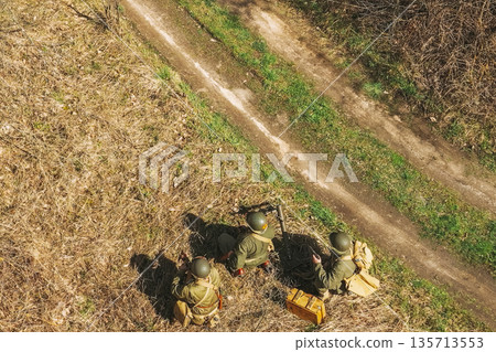 Men Dressed As US American Soldiers Of USA Infantry Of World War II sneaking around In spring Autumn Day. Soldiers prepare mortar for battle In dry grass. Aerial view elevated shot Men Dressed As US American Soldiers Of USA Infantry Of World War II sneaking around In spring Autumn Day. Soldiers prepare mortar for battle In dry grass. Aerial view elevated shot 135713553