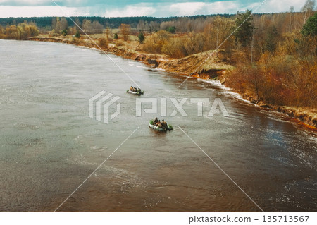 Men Dressed As US American Soldiers Of USA Infantry Of World War II carry out rafting on rubber boats In spring Autumn Day. Group of Soldiers people are preparing to disembark. Aerial view elevated Men Dressed As US American Soldiers Of USA Infantry Of World War II carry out rafting on rubber boats In spring Autumn Day. Group of Soldiers people are preparing to disembark. Aerial view elevated 135713567