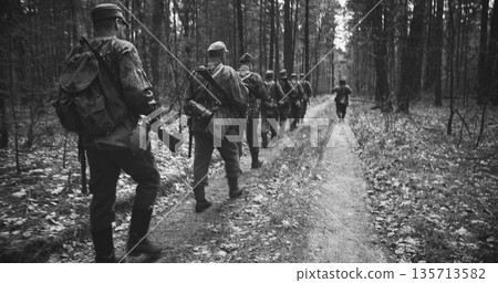 Group Of Reenactors Dressed As German Infantry Soldiers Marching By Forest Road Autumn Season. Reenactment Tactic Game. Wermacht German Military Uniform And Rifle During Ww2. Carabin Mauser 98k. Black 135713582