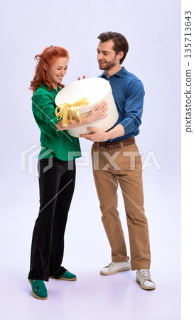 Man and woman holding large gift box together in studio. Man and woman holding large gift box together in studio. 135713643