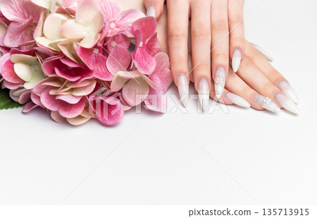 Woman showcasing elegant long almond nails with floral art Woman showcasing elegant long almond nails with floral art 135713915