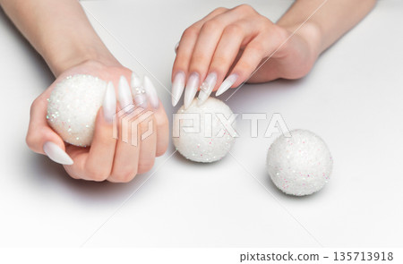 Woman hands holding sparkling christmas ornaments with long nails Woman hands holding sparkling christmas ornaments with long nails 135713918