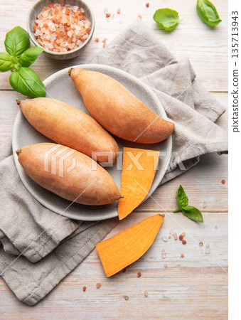 Raw sweet potatoes on plate, preparing healthy meal 135713943