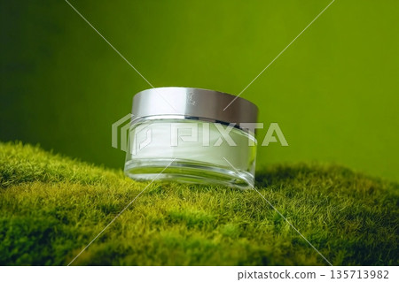A jar of white beauty cream in a container on green background. Cosmetic package mockup. Skin cosmetic product. A jar of white beauty cream in a container on green background. Cosmetic package mockup. Skin cosmetic product. 135713982