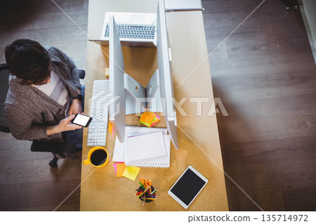 Male office worker checking smartphone while sitting at office desk with monitors, copy space Male office worker checking smartphone while sitting at office desk with monitors, copy space 135714972