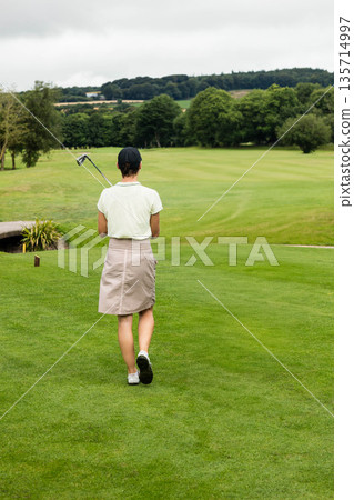 Mature female golfer standing on manicured fairway holding golf club over shoulder Mature female golfer standing on manicured fairway holding golf club over shoulder 135714997