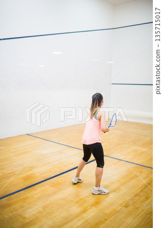 Squash racket is leaning against polished wooden floor in squash court, showing blue boundary lines 135715017