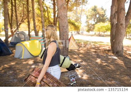 Woman holding rolled rug and sleeping mat while standing at campsite among pop-up tents, copy space Woman holding rolled rug and sleeping mat while standing at campsite among pop-up tents, copy space 135715134