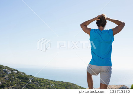 Man standing on ridge wearing blue sportswear gazing at sea horizon under clear sky, copy space Man standing on ridge wearing blue sportswear gazing at sea horizon under clear sky, copy space 135715180