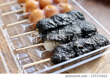 Skewers of dango in a plastic case: Sesame dango and mitarashi dango Skewers of dango in a plastic case: Sesame dango and mitarashi dango 135715622