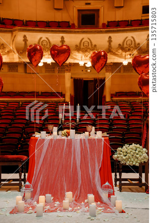 Romantic Valentine's Day Table Setup with Red Heart Balloons and Candles in an Elegant Theater Venue Romantic Valentine's Day Table Setup with Red Heart Balloons and Candles in an Elegant Theater Venue 135715803