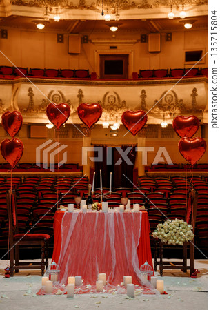Romantic Valentine's Day Dinner Setup with Red Heart Balloons in an Elegant Opera House Auditorium Romantic Valentine's Day Dinner Setup with Red Heart Balloons in an Elegant Opera House Auditorium 135715804