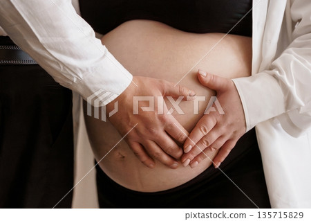 Pregnant woman and partner gently holding belly together in intimate moment, soft lighting, black and white clothing, emotional bonding scene Pregnant woman and partner gently holding belly together in intimate moment, soft lighting, black and white clothing, emotional bonding scene 135715829
