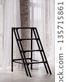 Modern Black Metal Ladder Stool in Minimalist Loft Interior with White Curtains and Exposed Brick Wall 135715861
