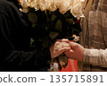 Romantic couple holding hands with white roses in warm lighting, intimate moment, soft textures, emotional connection, wedding proposal or anniversary celebration 135715891