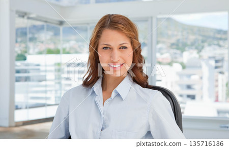 Woman sitting in office facing camera near glass windows, wearing light blue blouse, black chair Woman sitting in office facing camera near glass windows, wearing light blue blouse, black chair 135716186