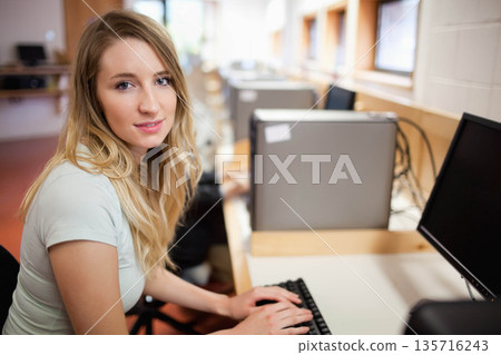 Woman sitting and typing at computer lab desk with keyboard, monitor, towers and cables Woman sitting and typing at computer lab desk with keyboard, monitor, towers and cables 135716243
