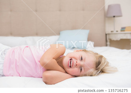 Female child lying on bed in softly lit bedroom, wearing pink sleeveless top, with headboard, lamp Female child lying on bed in softly lit bedroom, wearing pink sleeveless top, with headboard, lamp 135716275