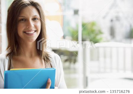 Teenage female standing left smiling and holding blue binder with yellow notes at lobby, copy space Teenage female standing left smiling and holding blue binder with yellow notes at lobby, copy space 135716276