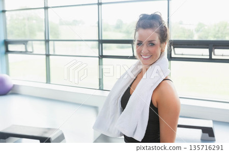 Woman standing towel around neck wearing black top in studio by windows, purple ball, copy space 135716291