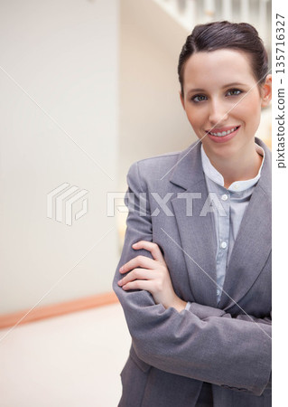 Female professional standing in office corridor wearing grey blazer and light shirt, copy space Female professional standing in office corridor wearing grey blazer and light shirt, copy space 135716327