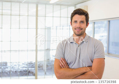 Man standing arms crossed wearing light gray polo in modern office by glass partition, copy space 135716398