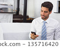 Adult man wearing white shirt, striped tie sitting on bench using smartphone at cafe, copy space 135716420